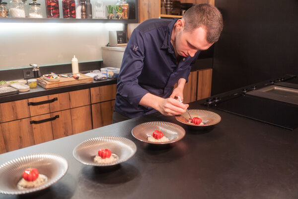 Ein jünger Koch verfeinert im letzten Arbeitsschritt Speisen in der Küche von Josephs Fine Dining